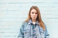 Portrait of a beautiful blonde girl on a blue background, looking into the camera with a serious face. Girl student in a jeans Royalty Free Stock Photo