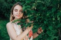 Portrait of a beautiful blonde girl with eyes closed and natural beauty in a green leaves trees. Copy, empty space for text Royalty Free Stock Photo