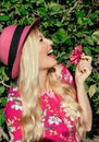 Portrait. Beautiful blonde girl in a hat laughs. Holding the flower in his hand. On open air. Behind her green foliage. It is illu