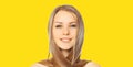 Portrait of beautiful blonde smiling young woman with long hair and cute smile on yellow background Royalty Free Stock Photo