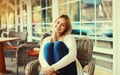 Portrait of beautiful blonde smiling young woman sitting on chair waiting in city cafe Royalty Free Stock Photo