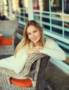 Portrait of beautiful blonde smiling young woman sitting on chair waiting in city cafe Royalty Free Stock Photo