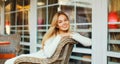 Portrait of beautiful blonde smiling young woman sitting on chair waiting in city cafe Royalty Free Stock Photo