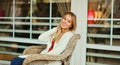 Portrait of beautiful blonde smiling young woman sitting on chair waiting in city cafe Royalty Free Stock Photo