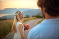 portrait of beautiful blonde turned around in motion with red bouquet in her hands and wreath of flowers on her head, smiling,