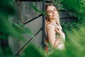 Portrait of a beautiful blonde woman with eyes closed and natural beauty in a green leaves trees on a wooden wall background. Copy Royalty Free Stock Photo