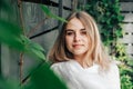 Portrait of a beautiful blonde woman in a green leaves trees on a wooden wall background. Copy, empty space for text Royalty Free Stock Photo