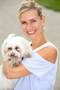 Portrait of blonde woman holding a cute little white dog Royalty Free Stock Photo