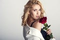 Portrait of the beautiful blonde woman with long blonde hair, perfect skin, keeps the face of a bouquet of red roses flowers, Royalty Free Stock Photo