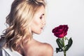 Portrait of the beautiful blonde woman with long blonde hair, perfect skin, keeps the face of a bouquet of red roses flowers, Royalty Free Stock Photo