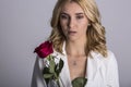 Portrait of the beautiful blonde woman with long blonde hair, perfect skin, keeps the face of a bouquet of red roses flowers, Royalty Free Stock Photo