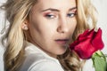 Portrait of the beautiful blonde woman with long blonde hair, perfect skin, keeps the face of a bouquet of red roses flowers, Royalty Free Stock Photo