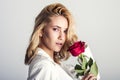 Portrait of the beautiful blonde woman with long blonde hair, perfect skin, keeps the face of a bouquet of red roses flowers, Royalty Free Stock Photo