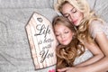 Portrait of the beautiful blonde woman mother and daughter on the beautiful face and amazing eyes lie sleeping on a bed in an eleg Royalty Free Stock Photo