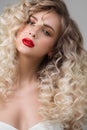 Portrait of a beautiful blonde woman with red lipstick on her lips. Curly blond long hair. Hairstyle Royalty Free Stock Photo