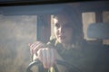 Portrait of beautiful blonde woman sitting at the wheel of car taken from behind the window