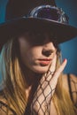 Portrait of a beautiful blonde woman wearing a fedora hat and fishnet gloves