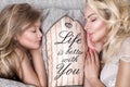 Portrait of the beautiful blonde woman mother and daughter on the beautiful face and amazing eyes lie sleeping on a bed in an eleg Royalty Free Stock Photo