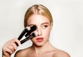 Portrait of beautiful blonde young woman face holding make up brushes. Spa model girl with clean skin isolated on a gray Royalty Free Stock Photo