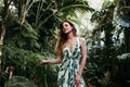 Portrait of beautiful blonde young woman smiling at sunset in a green house surrounded by tropical plants. Happiness and lifestyle Royalty Free Stock Photo