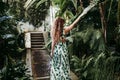 Portrait of beautiful blonde young woman smiling at sunset in a green house surrounded by tropical plants. Happiness and lifestyle Royalty Free Stock Photo