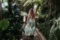 Portrait of beautiful blonde young woman smiling at sunset in a green house surrounded by tropical plants. Happiness and lifestyle Royalty Free Stock Photo