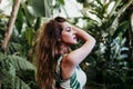 Portrait of beautiful blonde young woman smiling at sunset in a green house surrounded by tropical plants. Happiness and lifestyle Royalty Free Stock Photo