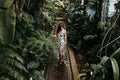 Portrait of beautiful blonde young woman smiling at sunset in a green house surrounded by tropical plants. Happiness and lifestyle Royalty Free Stock Photo