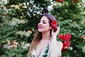 Portrait of beautiful blonde young woman smiling at sunset. Playing with red flowers. Happiness and lifestyle concept outdoors Royalty Free Stock Photo