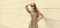 Portrait of beautiful blonde young woman wearing leopard dress and sunglasses on wall background Royalty Free Stock Photo