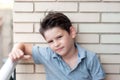 Portrait of a beautiful boy in a brick wall. Confident child, ha