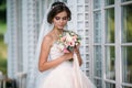 Portrait of beautiful bride with bouquet flowers in white luxury dress. Gorgeous model with bridal makeup and hairstyle