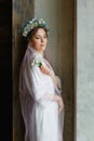 A portrait of a beautiful bride with her eyes closed with a wedding hairstyle and makeup with a veil and a wreath of flowers. Royalty Free Stock Photo