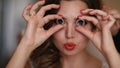 Portrait of the beautiful bride holding the wedding rings in the front of eyes and making funny faces.