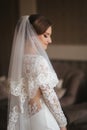 Portrait of beautiful bride standing by the window at home. Charming bride in white wedding dress Royalty Free Stock Photo