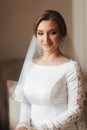 Portrait of beautiful bride standing by the window at home. Charming bride in white wedding dress Royalty Free Stock Photo