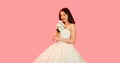 Portrait of beautiful bride woman with bouquet of flowers wearing white wedding dress on pink background Royalty Free Stock Photo