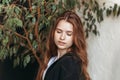 Portrait of a beautiful brooding young girl with long hair in an apartment with plants