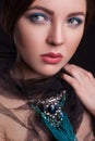 Portrait of beautiful brunette fashion model with black veil and blue jewelry and makeup and red lips in black bakground Royalty Free Stock Photo