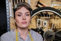 Portrait of a beautiful brunette female wearing working clothes, apron and goggles, standing in a workshop. Royalty Free Stock Photo