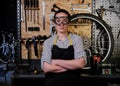 Portrait of a beautiful brunette female wearing working clothes, apron and goggles, standing in a workshop. Royalty Free Stock Photo