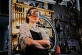 Portrait of a beautiful brunette female wearing working clothes, apron and goggles, standing in a workshop. Royalty Free Stock Photo