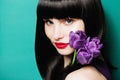 Portrait of a beautiful brunette girl with a lilac tulip on a blue background