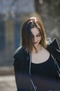 Portrait of a beautiful brunette girl walking in the spring in the park. Casual relaxed pose. Vertical photo