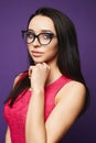 Portrait of beautiful brunette model girl with professional makeup, in fashionable black glasses and in red dress holds Royalty Free Stock Photo
