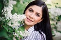 Portrait of a beautiful brunette whith a flowering tree. A young smiling woman against the background of spring blooming apple Royalty Free Stock Photo