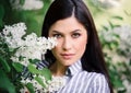 Portrait of a beautiful brunette whith a flowering tree. A young woman against the background of spring blooming apple trees. Royalty Free Stock Photo