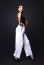 Portrait of beautiful brunette woman in a black blouse and white pants,. Fashion photo shot. Royalty Free Stock Photo