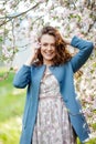 Portrait of a beautiful brunette women in blue jacket  in blossom apple tree garden in spring time. Enjoy Nature. Healthy smiling Royalty Free Stock Photo