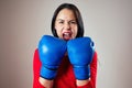 Portrait of a beautiful brunette woman with a furious face with boxing gloves on her hands in the gym. athlete with